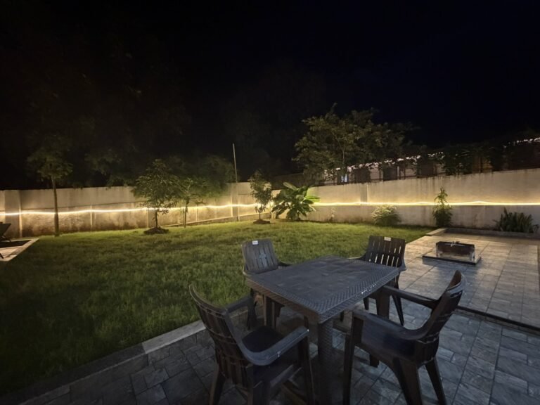 Nandan Villa, Karjat: Outdoor table for four beside the lit lawn